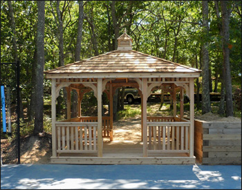 12 x 12 Cedar Rectangular Gazebo shown with red cedar deck, 1x3 standard railings, straight posts, straight fascia, cedar shake shingles, unstained, stainless steel hardware, additional entrance, 8 bench sections and cupola. 