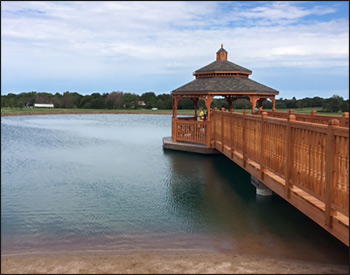 14 Cedar Octagon Double Roof Gazebo shown with 2 x 3 Decorative Spindle Railings, 36" High Railings, Decorative Posts, Cedar Tone Stain/Sealer, Additional Entrance, and Rustic Cedar Asphalt Shingles.Also shown: TWO Custom  5 x 17 Bridges – spliced together at center to created 5x34’ bridge with a Cedar Deck, Cedar 2 x 3 Decorative Spindle Railings, 42" High Rails, Cedar Beam Wrap, and Cedar Tone Stain/Sealer