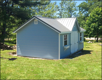 Slate Blue Vinyl Chalet Shed shown with Charcoal Metal Roof, 2 18" X 36" Vertical Sliding Windows on Each Side of the Door, a Pair of Aluminum Gable Vents, a 3 Steel Slab 9 Lite Door, 6 Vinyl Sided Double Door, 2 Pairs of Shutters, 2 Flower Boxes, and an Octagon Window Above the Door.